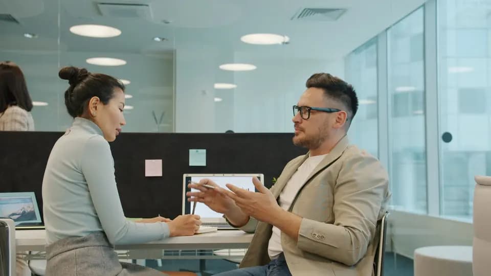Two colleagues in conversation in an open-plan office