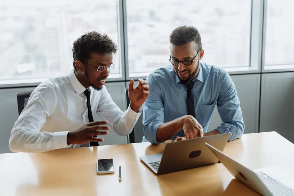 Two colleagues working through something on a shared laptop