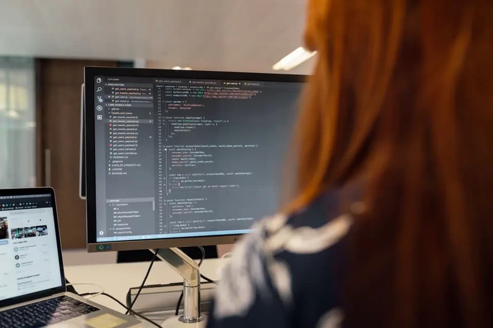 A software engineer writing code at an office workstation