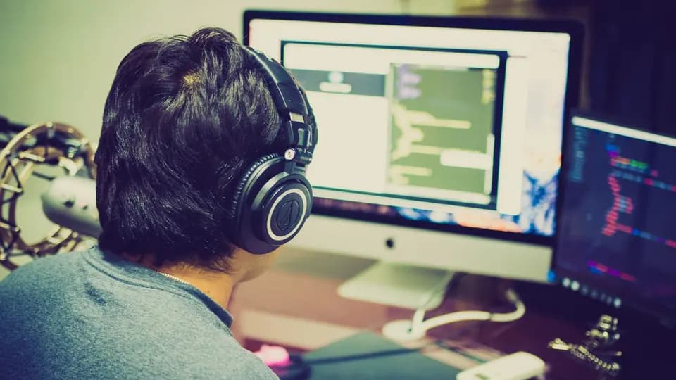 A developer in headphones working across two monitors