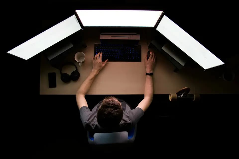 An engineer working across three monitors