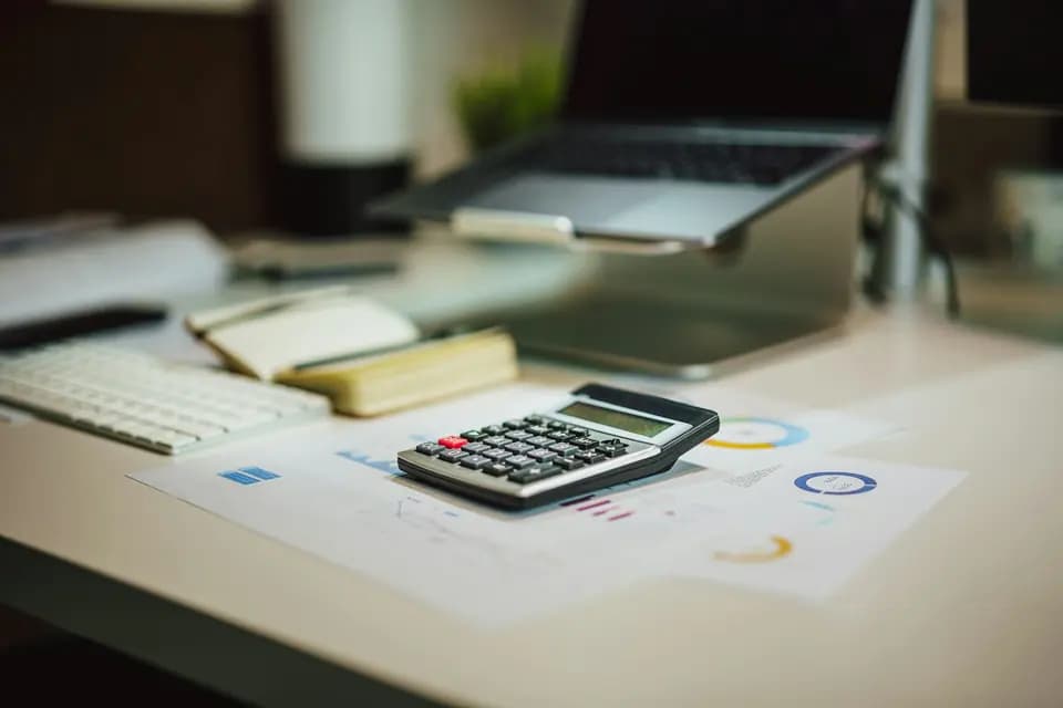 A calculator sitting beside a laptop on a desk