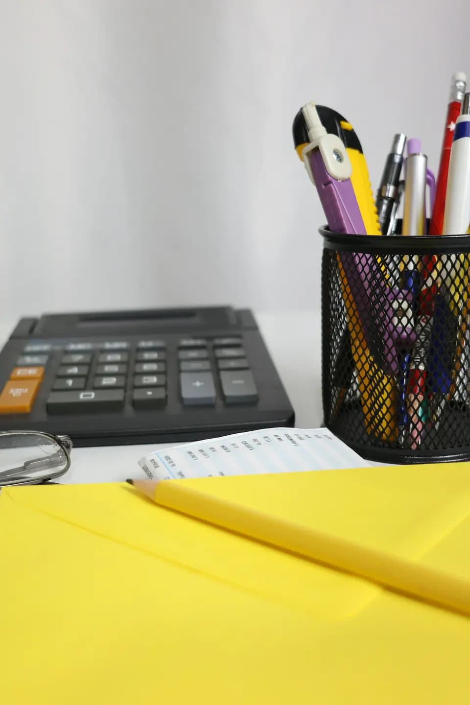 A calculator, pens and an envelope laid out on a desk
