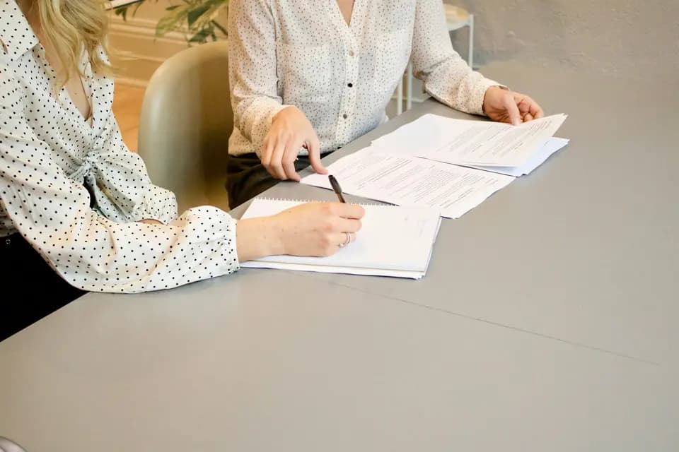 A document being signed with a colleague looking on