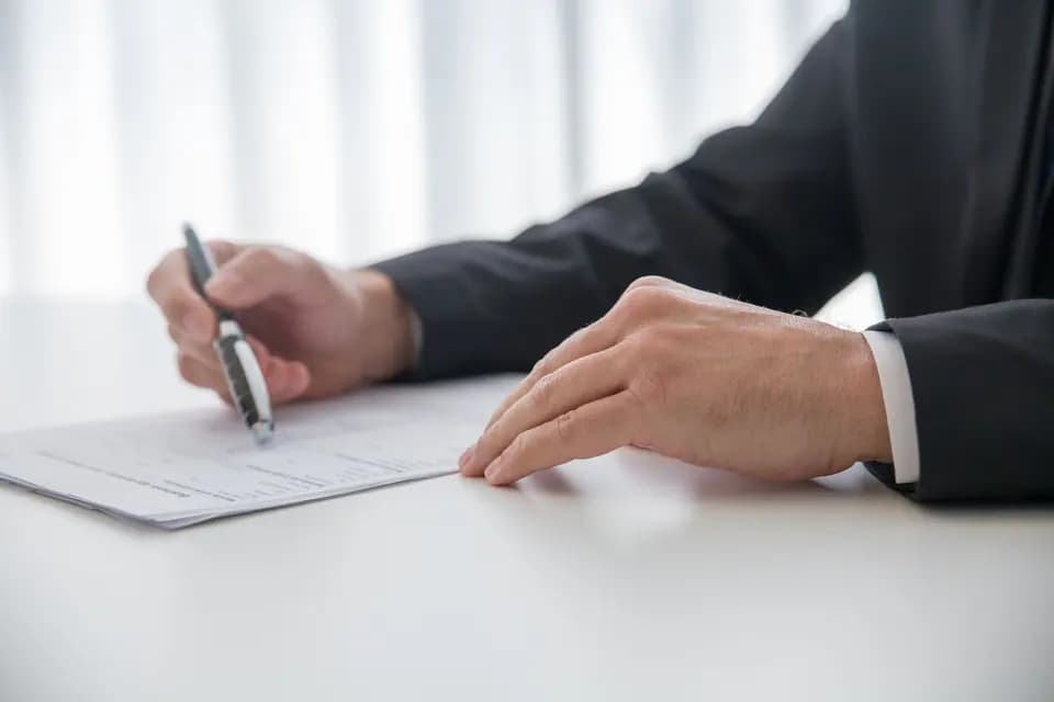 A colleague signing paperwork at an office desk