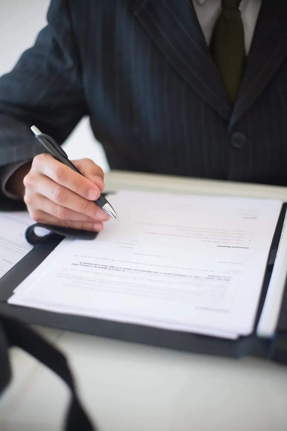 A hand signing a business document with a pen