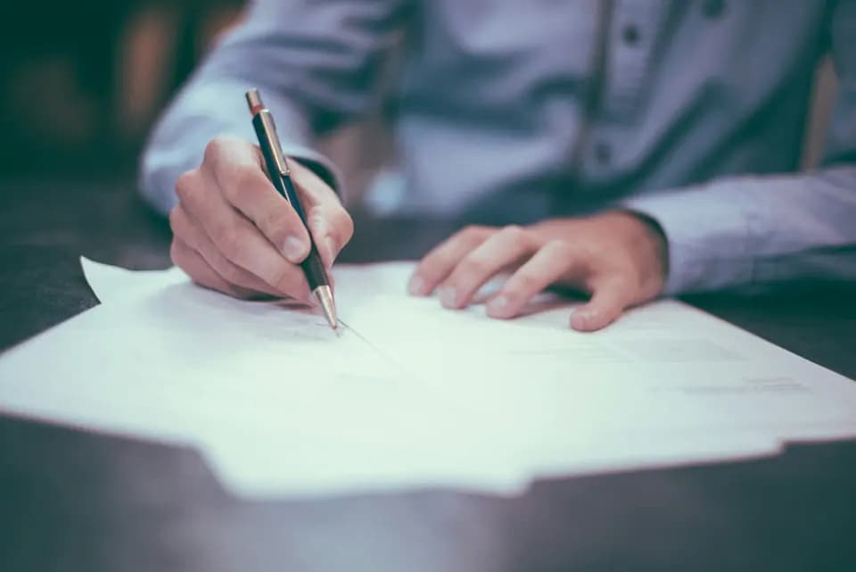 Someone working through a printed agreement with a pen