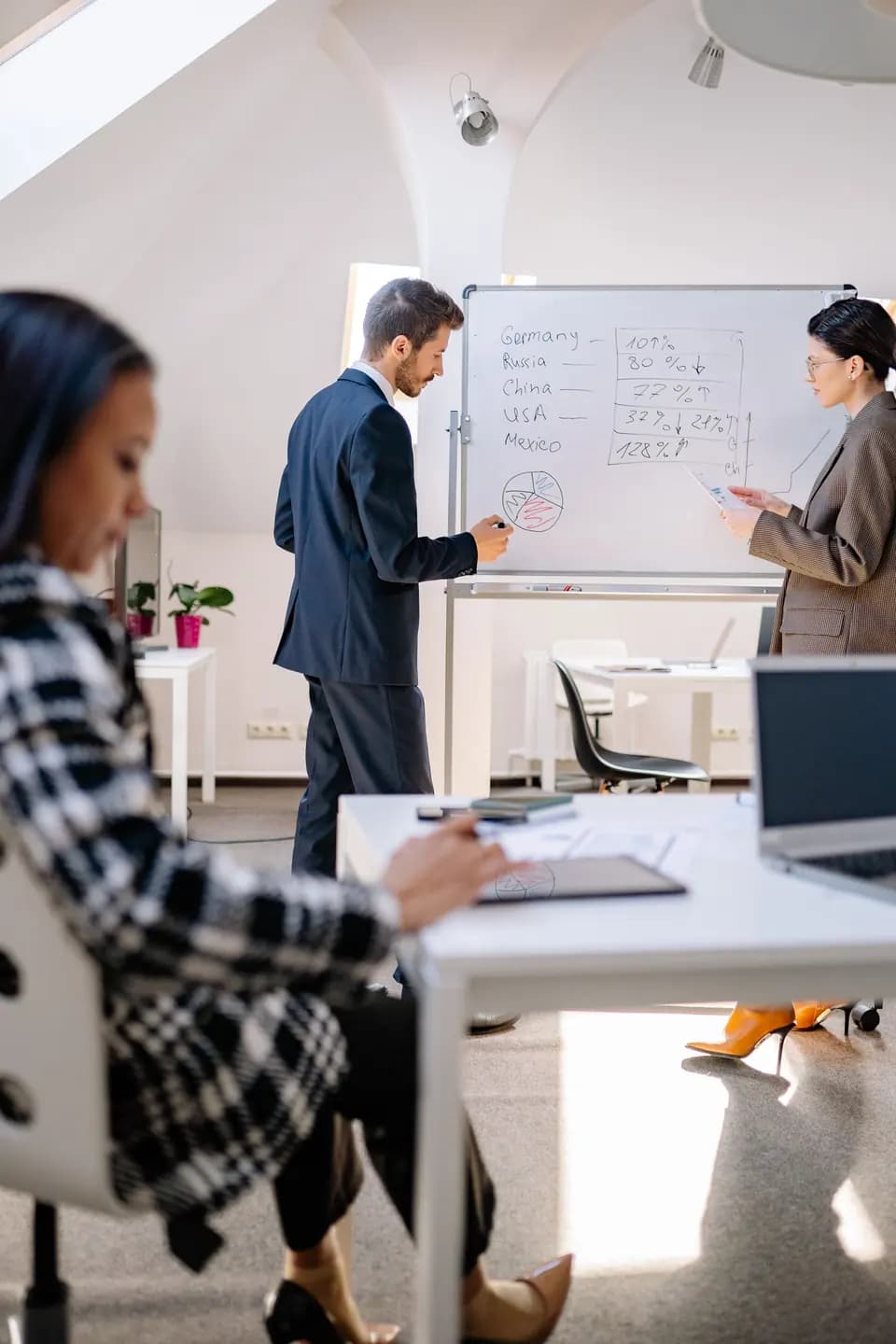 Two colleagues reviewing figures at a whiteboard
