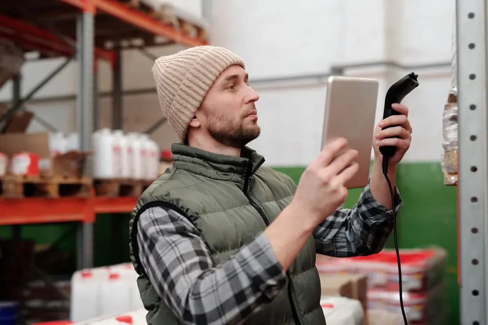 A worker in a hi-vis vest scanning stock with a handheld barcode reader