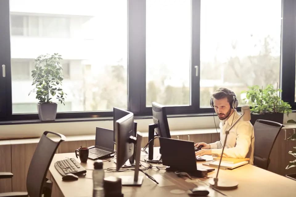 A support engineer in a headset working across several monitors
